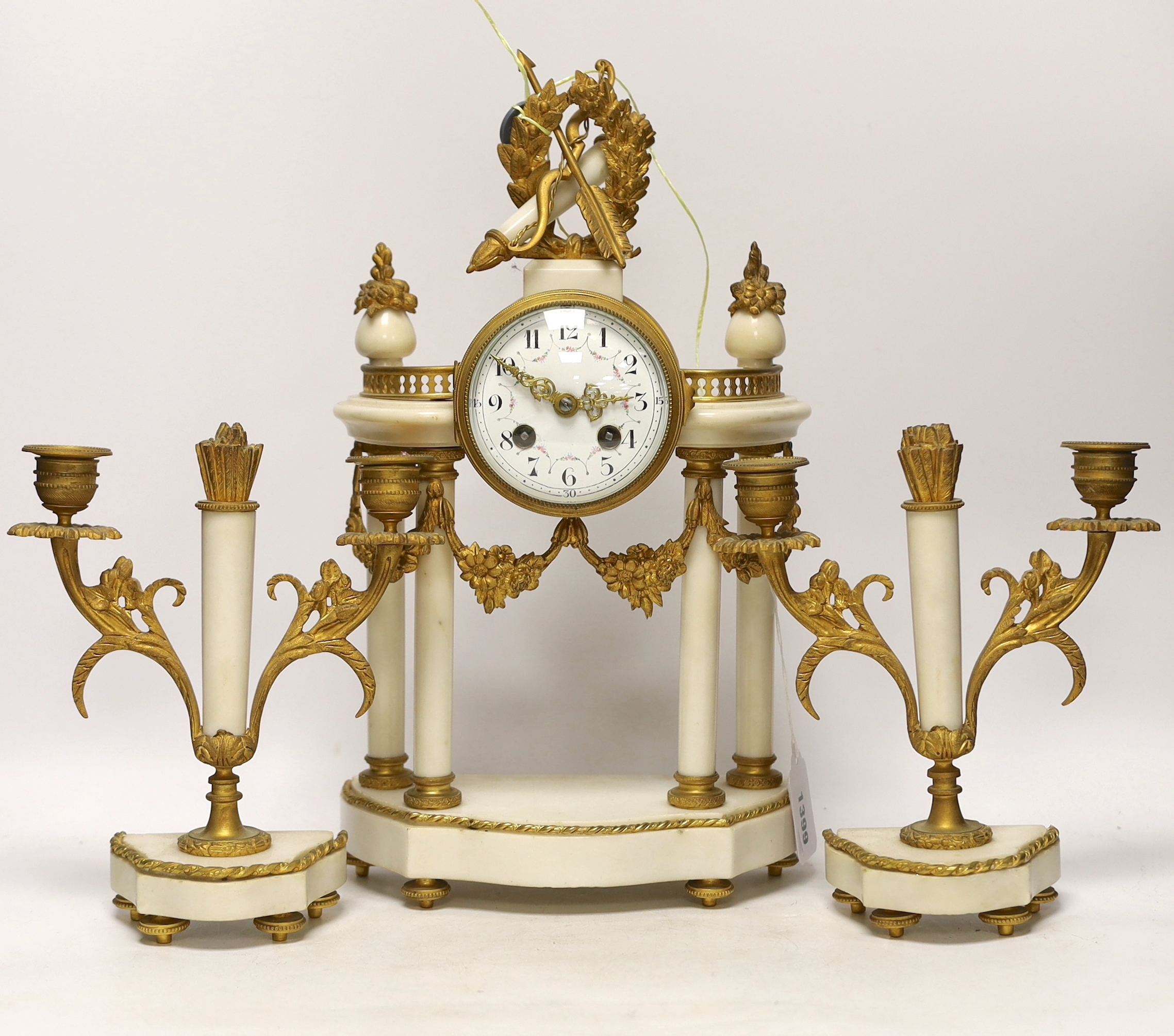 A French ormolu and white marble clock garniture, c.1900, striking on a gong, the dial decorated with swags, 40cm high